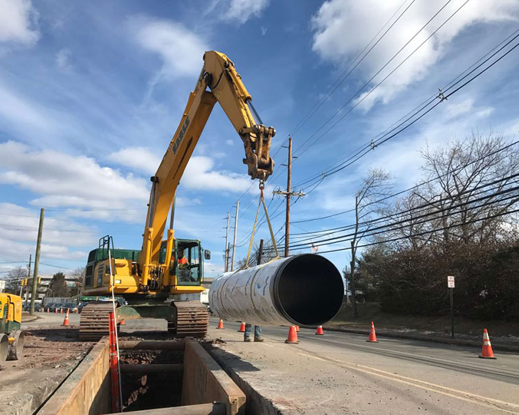 An Earle crane lowers pipe into trench boxes for Earle's sewer division. NJ.